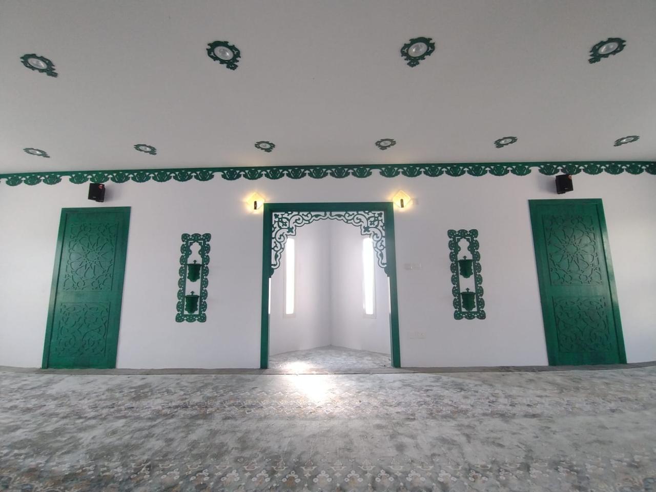 مسجد الربيع بنت معوذ رضي الله عنها — قاعة الصلاة والسجاد والإطارات الخضراء حول الفتحات